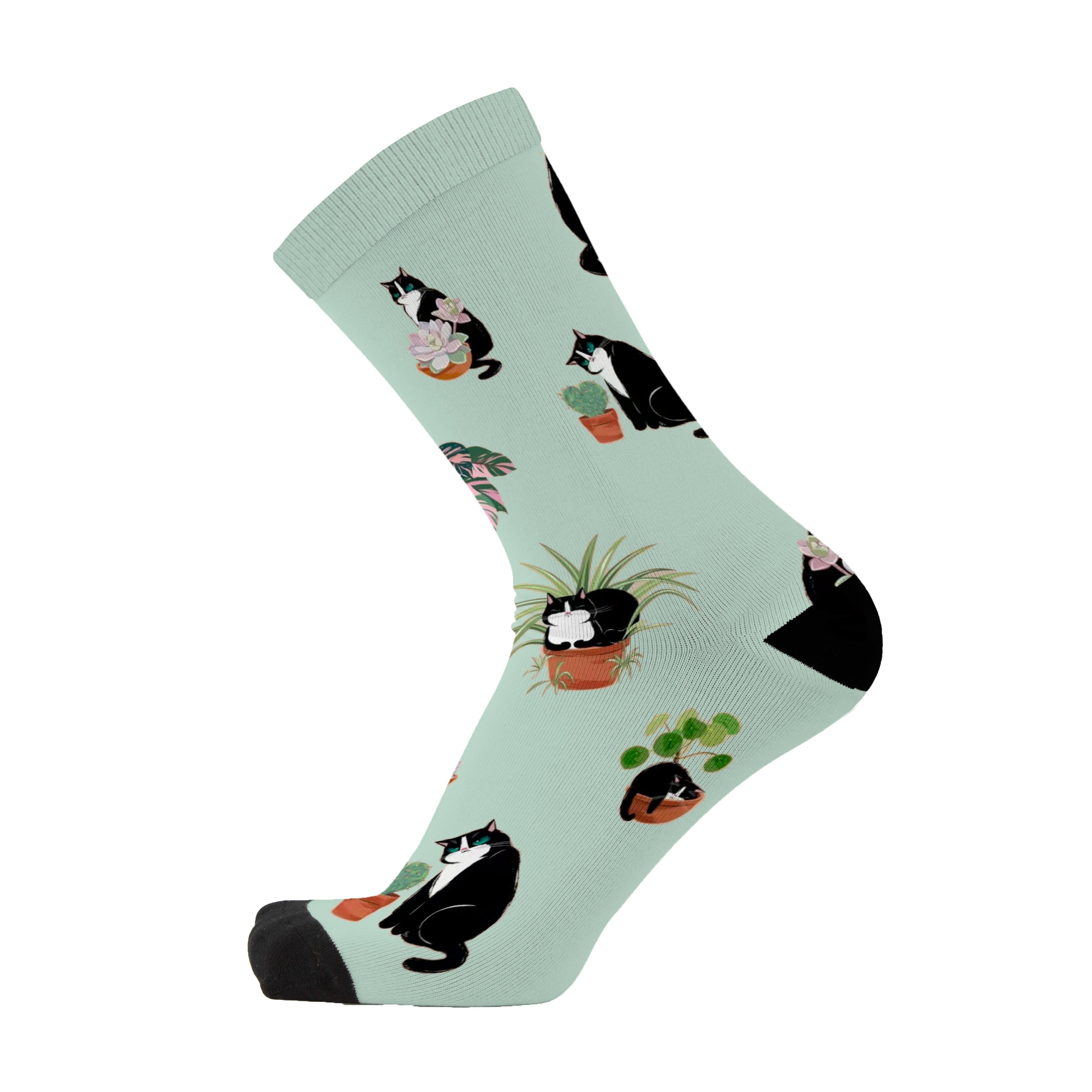 Single mint green sock shown side-on, with a black-and-white cat and a potted fern in the print.