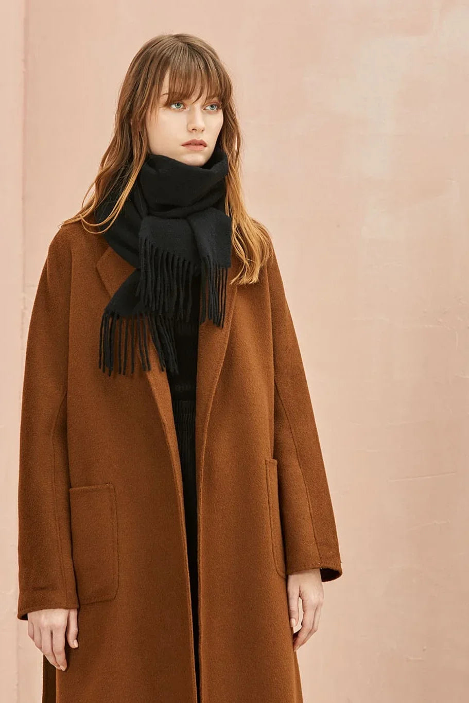 Ebony black merino scarf worn over a camel coat with fringe at the hem