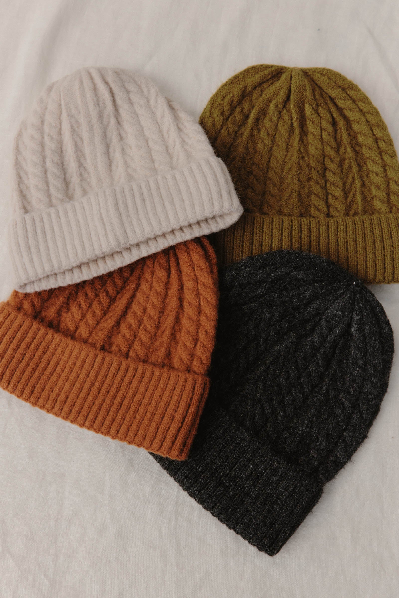 Four Palmer Beanies laid flat in cream, olive, rust and charcoal