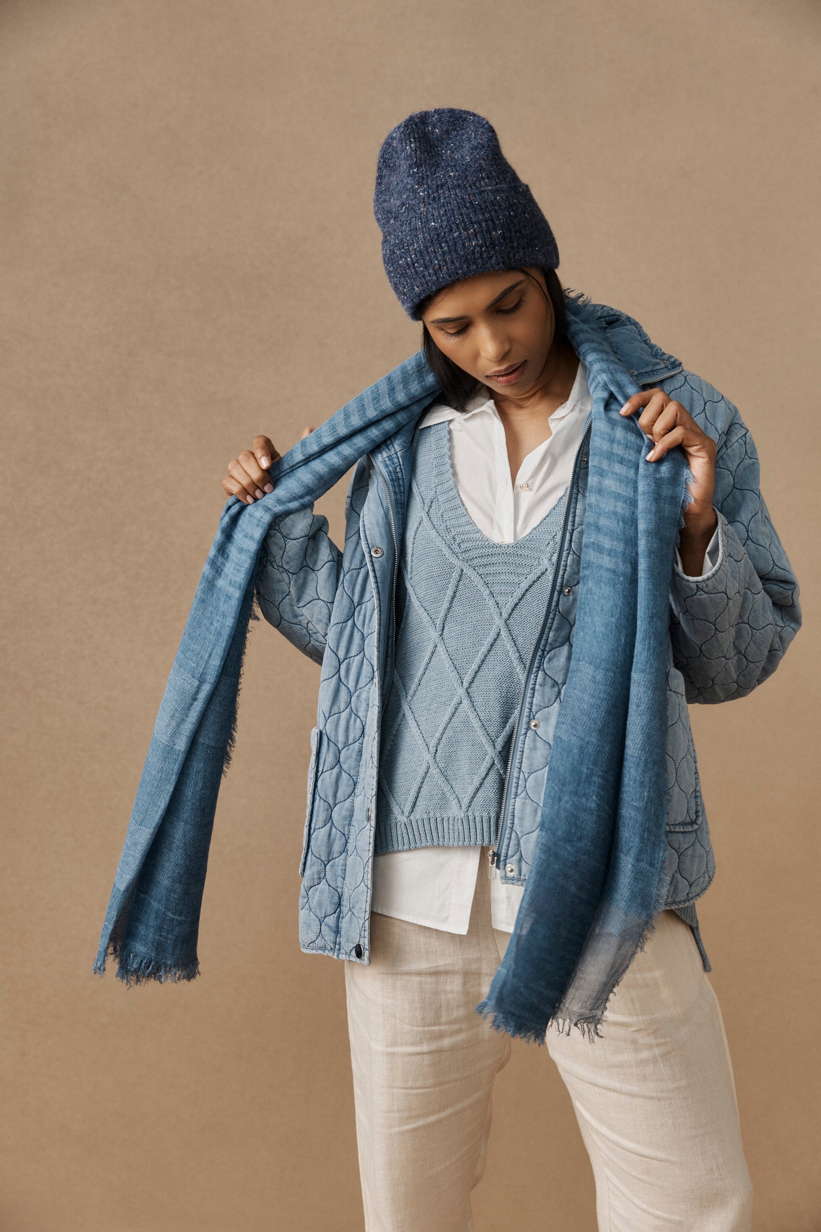 Model tying a scarf while wearing the denim Zarda Beanie