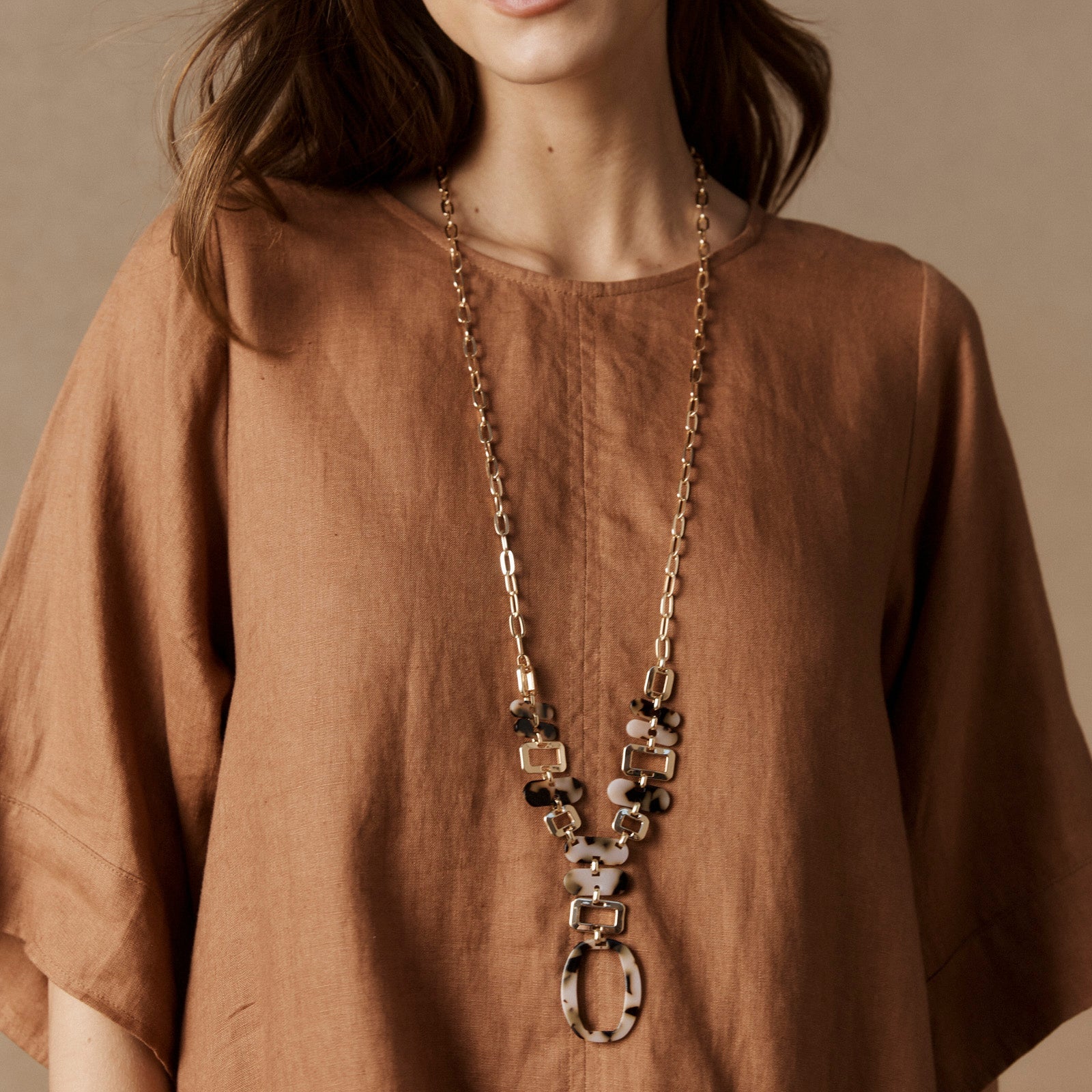 Model wearing the Nomad Chain over a rust linen dress
