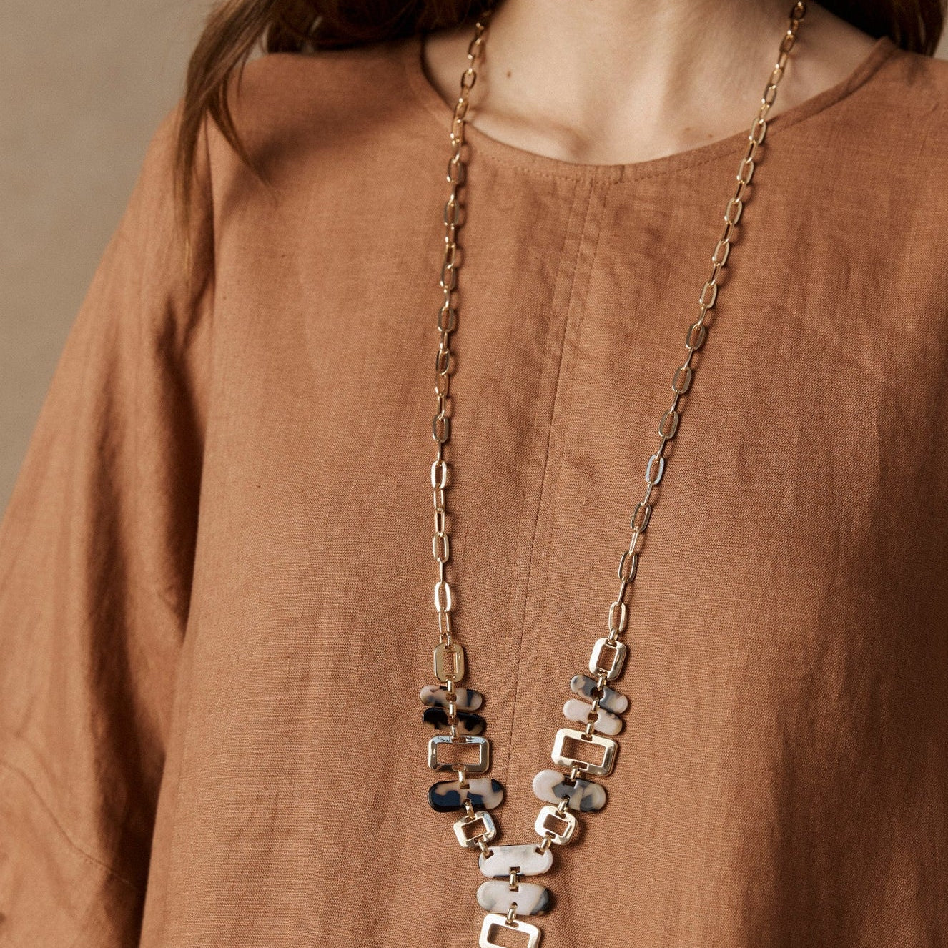 Model in a rust linen top wearing the long Nomad Chain