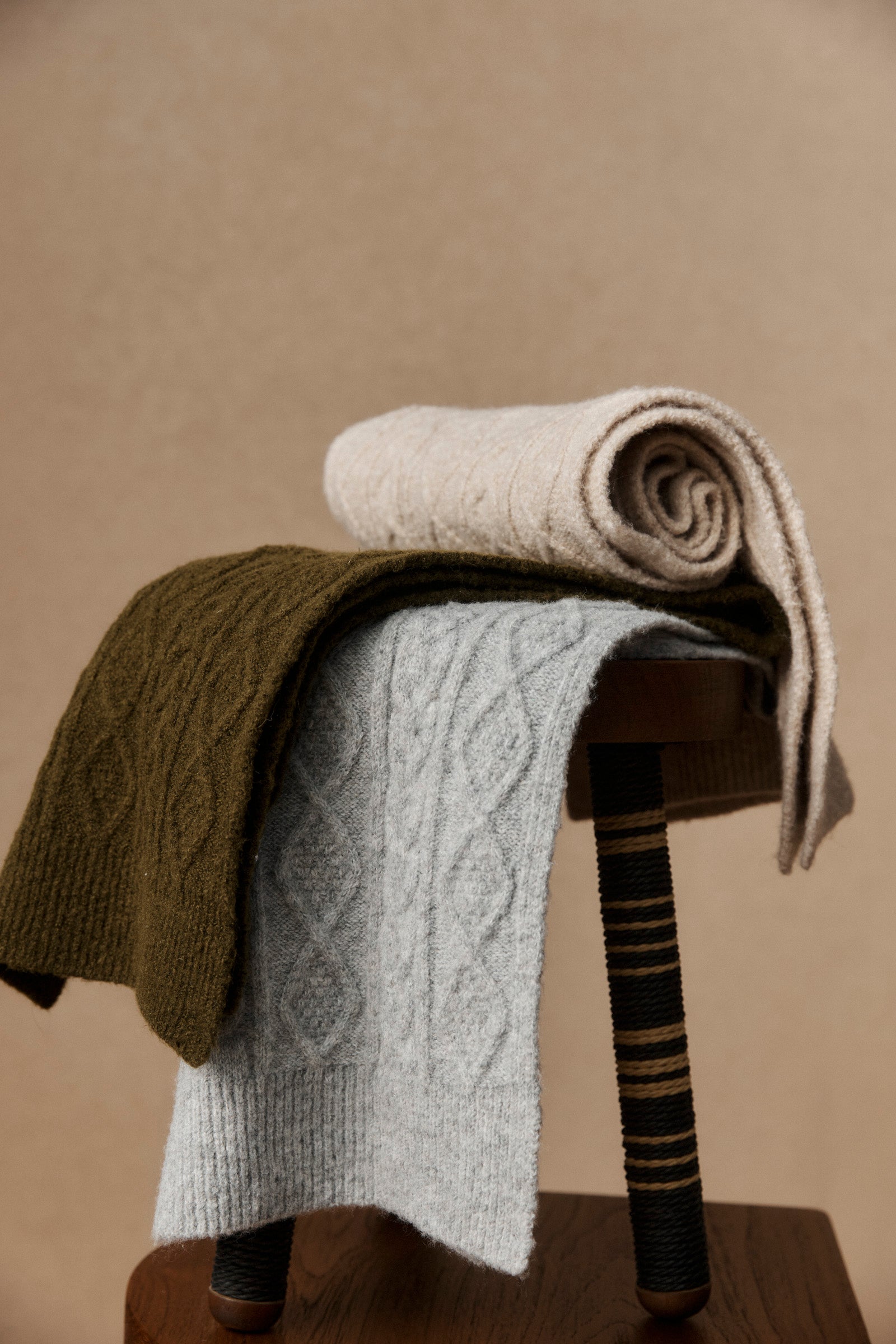 Rolled and draped scarves in cream, olive and grey on a chair