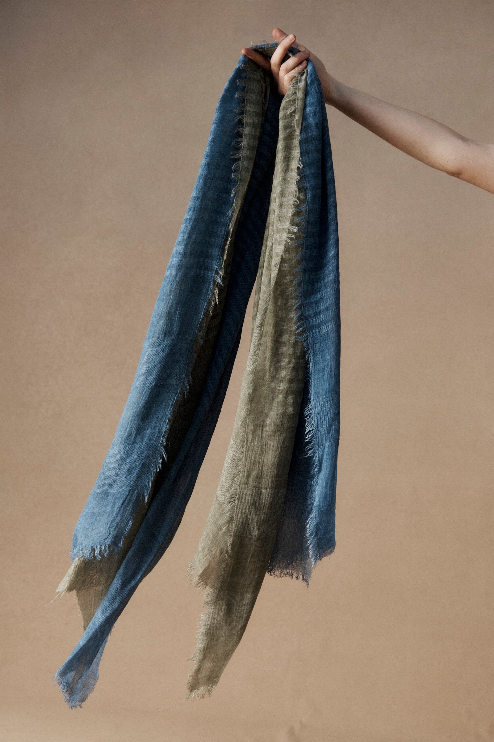 Hand holding Bodhi Scarves in lake and sage colourways
