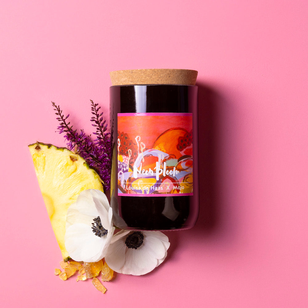 Neon Bloom limited-edition candle with colourful Louisa de Haas label, styled with pineapple and anemones on pink