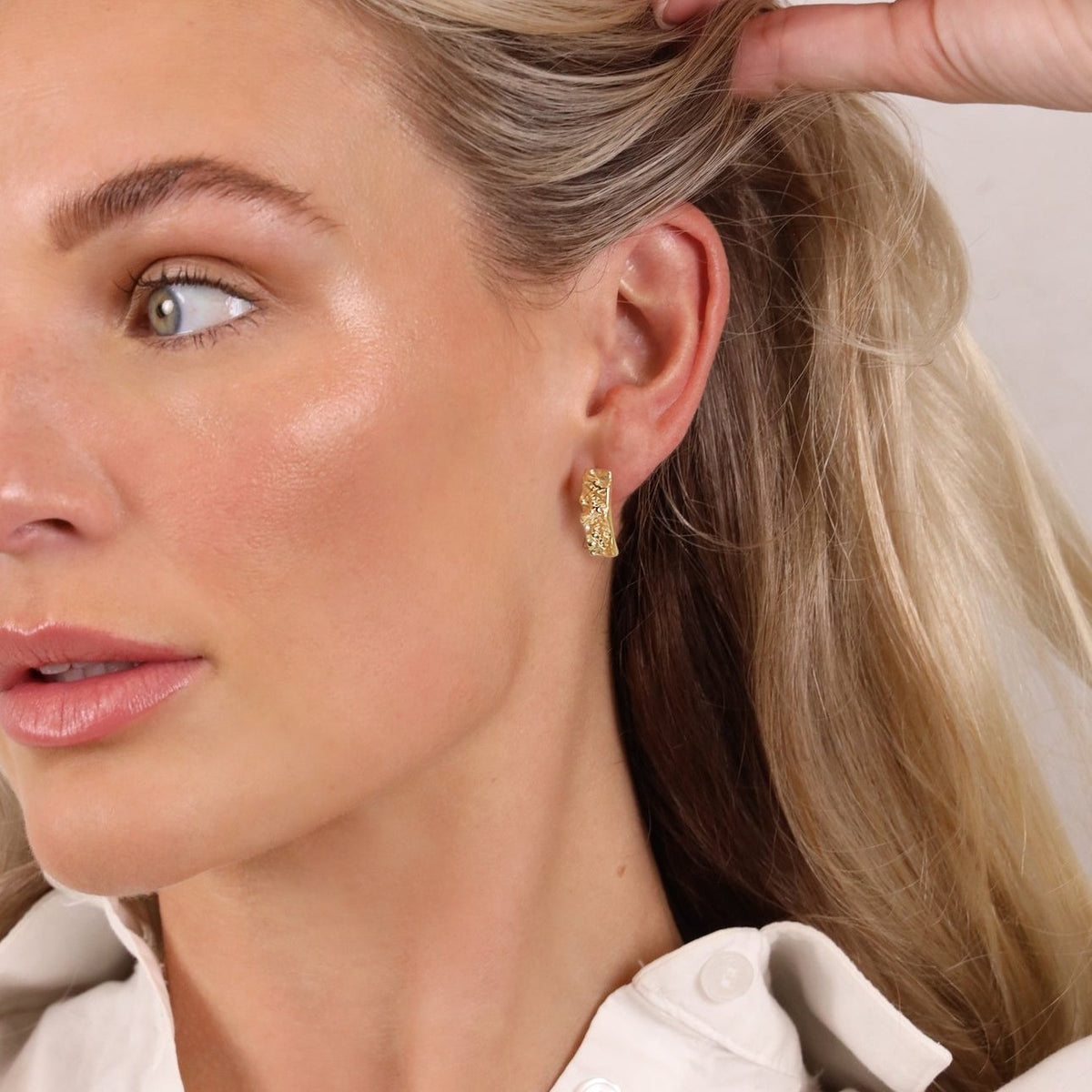 Model wearing a Bella gold textured earring, hair swept back