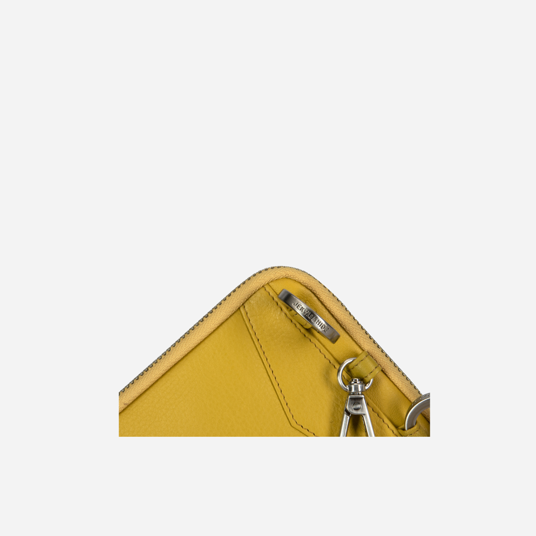 Corner close-up of the yellow pouch zip and strap clip
