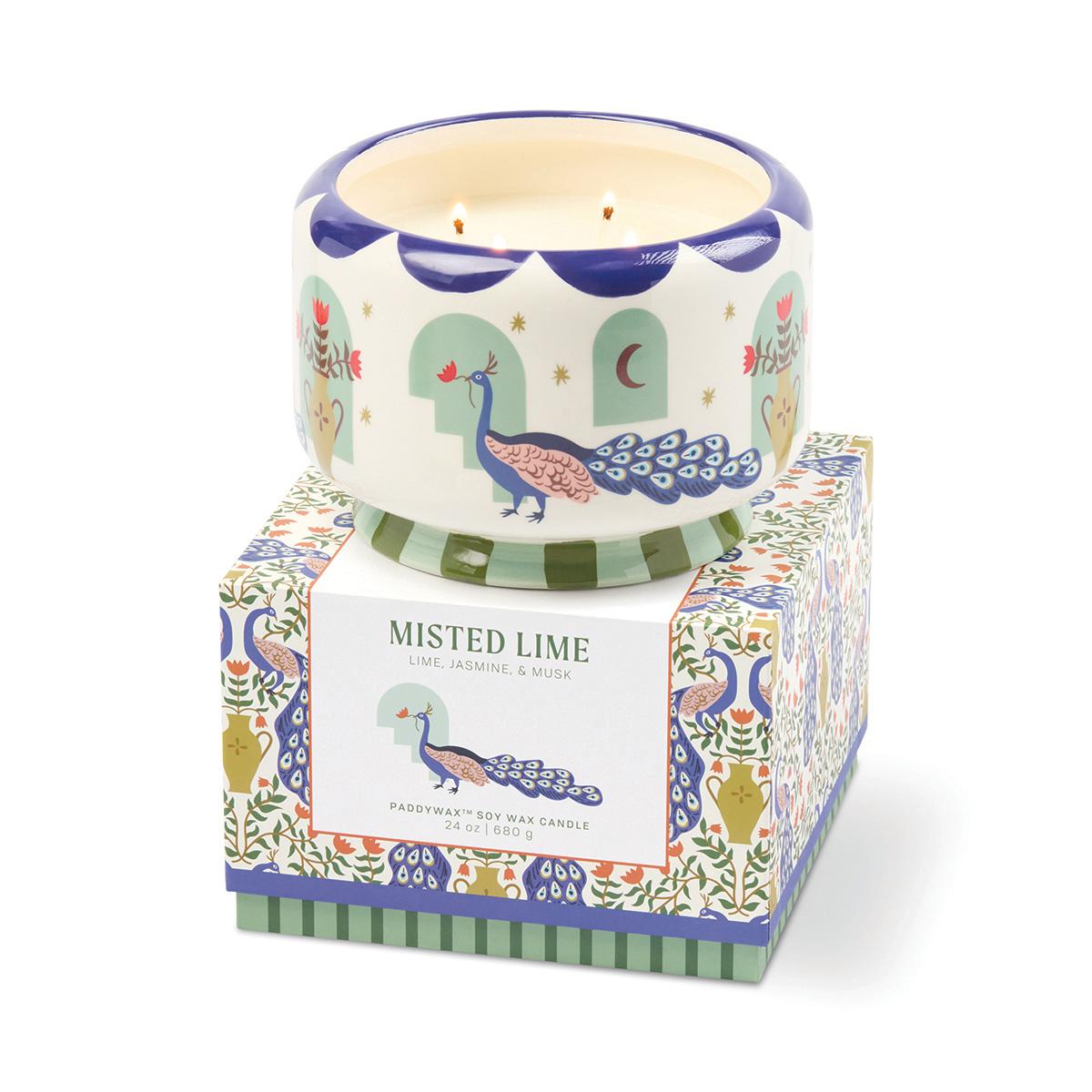 The peacock candle sitting on its Misted Lime gift box, printed with peacocks, urns and flowers.