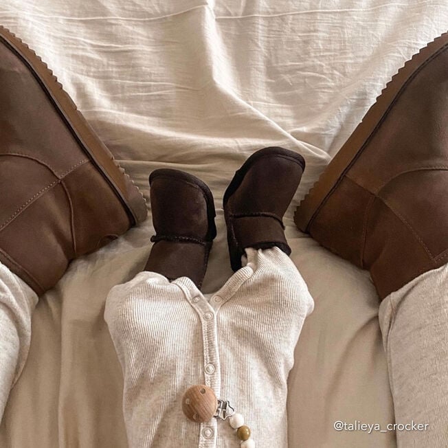 Baby lying between two adults wearing chocolate sheepskin booties