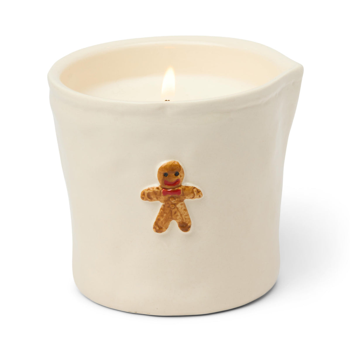 Cream ceramic tumbler candle with a raised gingerbread man in a red bow on the front, lit.