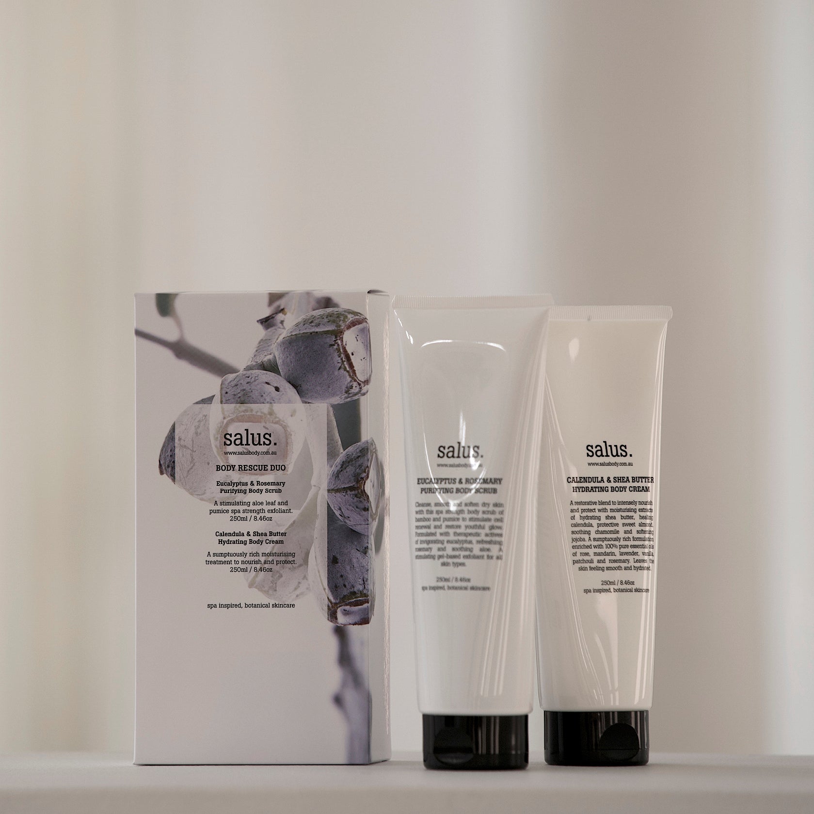 Salus Body Rescue Duo scrub and body cream tubes standing in front of the gift box