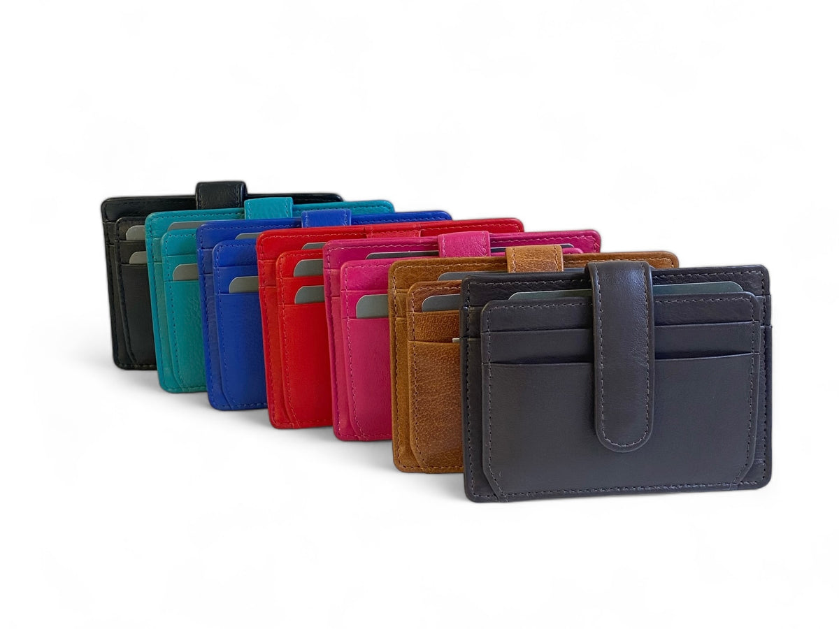 Leather card holders standing in a fanned row in black, aqua, cobalt, red, pink and brandy, a charcoal one at the front