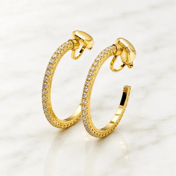 Pair of gold-tone open hoop clip-on earrings lined with clear crystals, on white marble