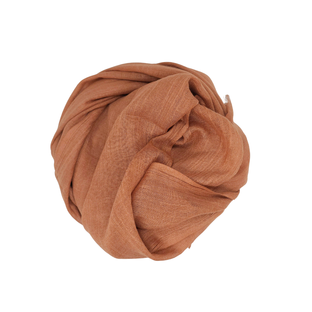 Beauty in Bamboo scarf in a coppery rust-brown, coiled into a round bundle