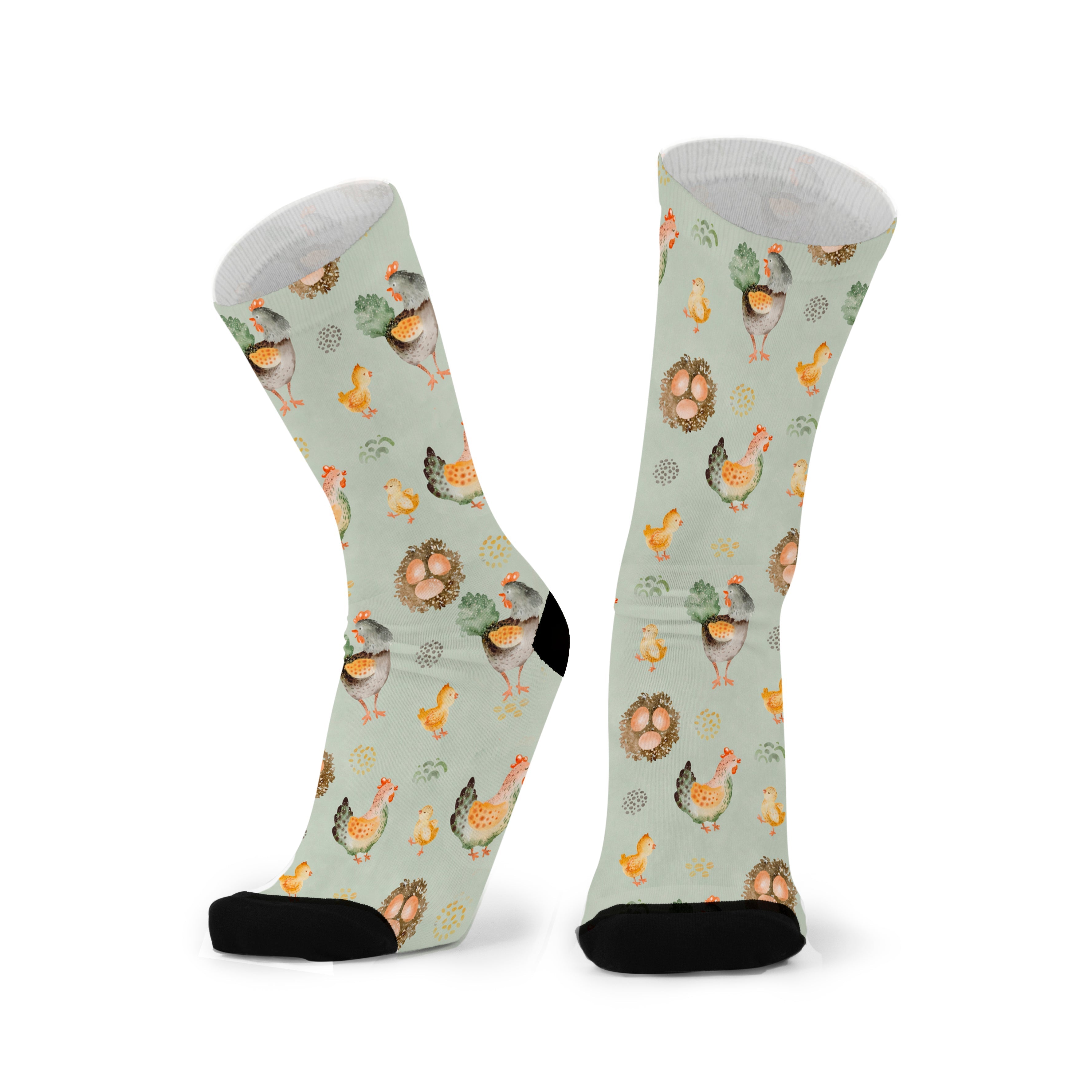 Pair of sage green socks stood side by side, showing the full repeating pattern of hens, chicks and nests wrapping around both socks.