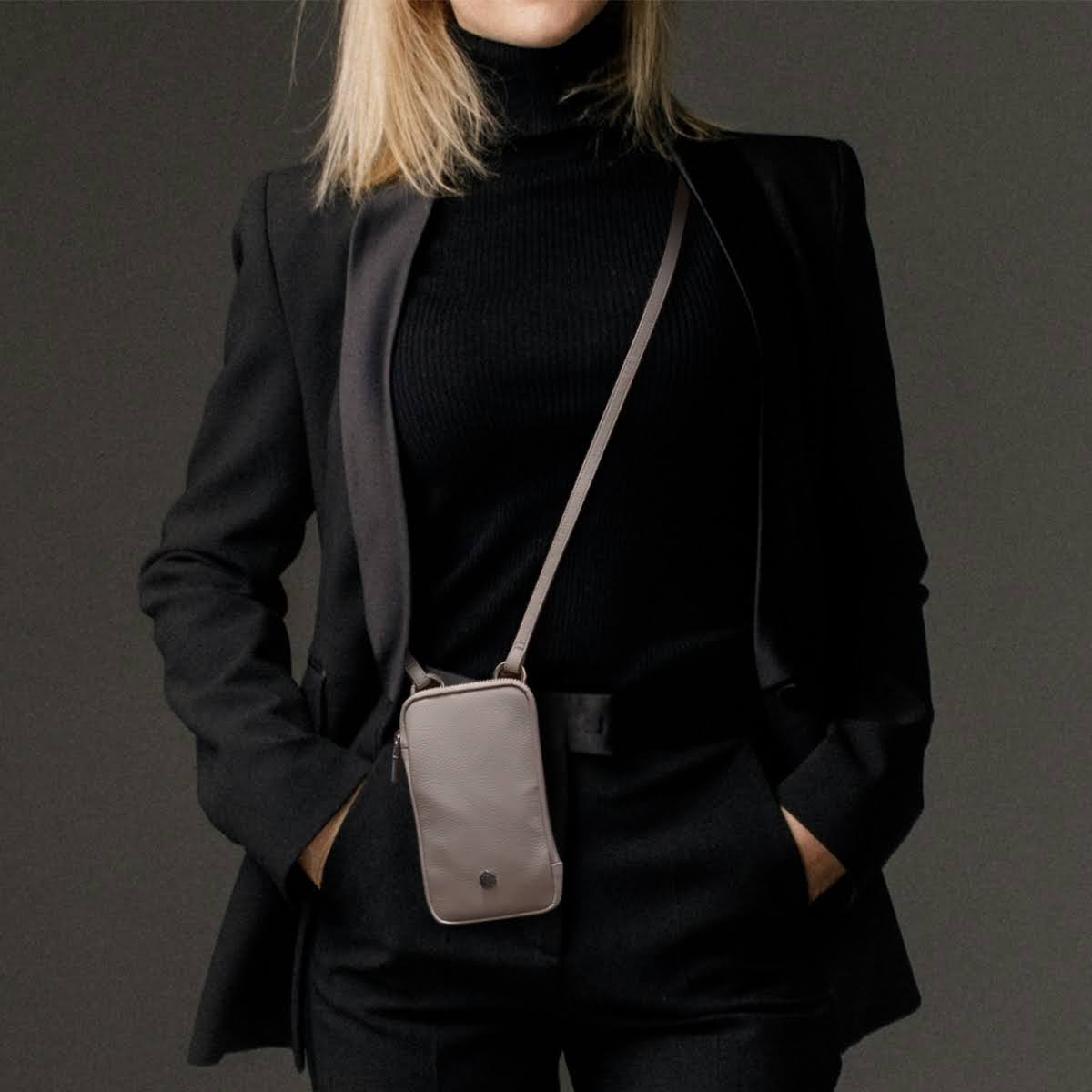 Woman in a black suit wearing the driftwood phone pouch crossbody