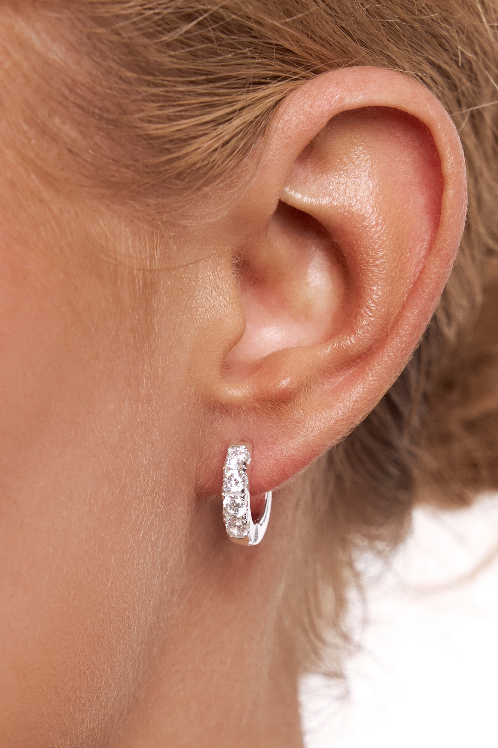 Close-up of a model's ear wearing a silver Lyla crystal huggie.