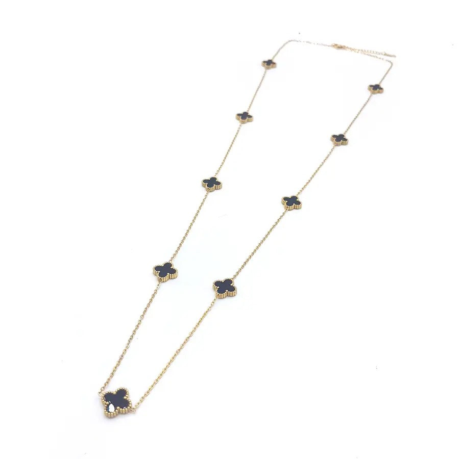 Long gold-tone chain necklace with small black four-leaf clovers spaced along it, on white