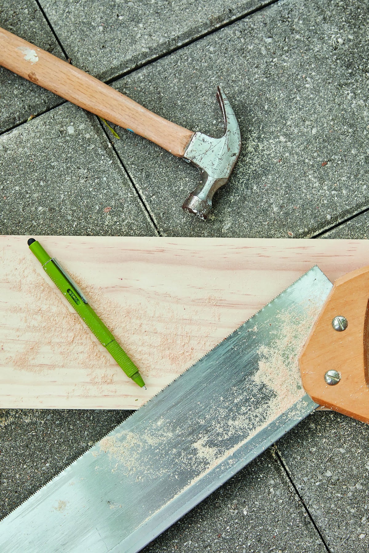 Olive green tooling pen on a sawn timber board with a hammer and a saw blade