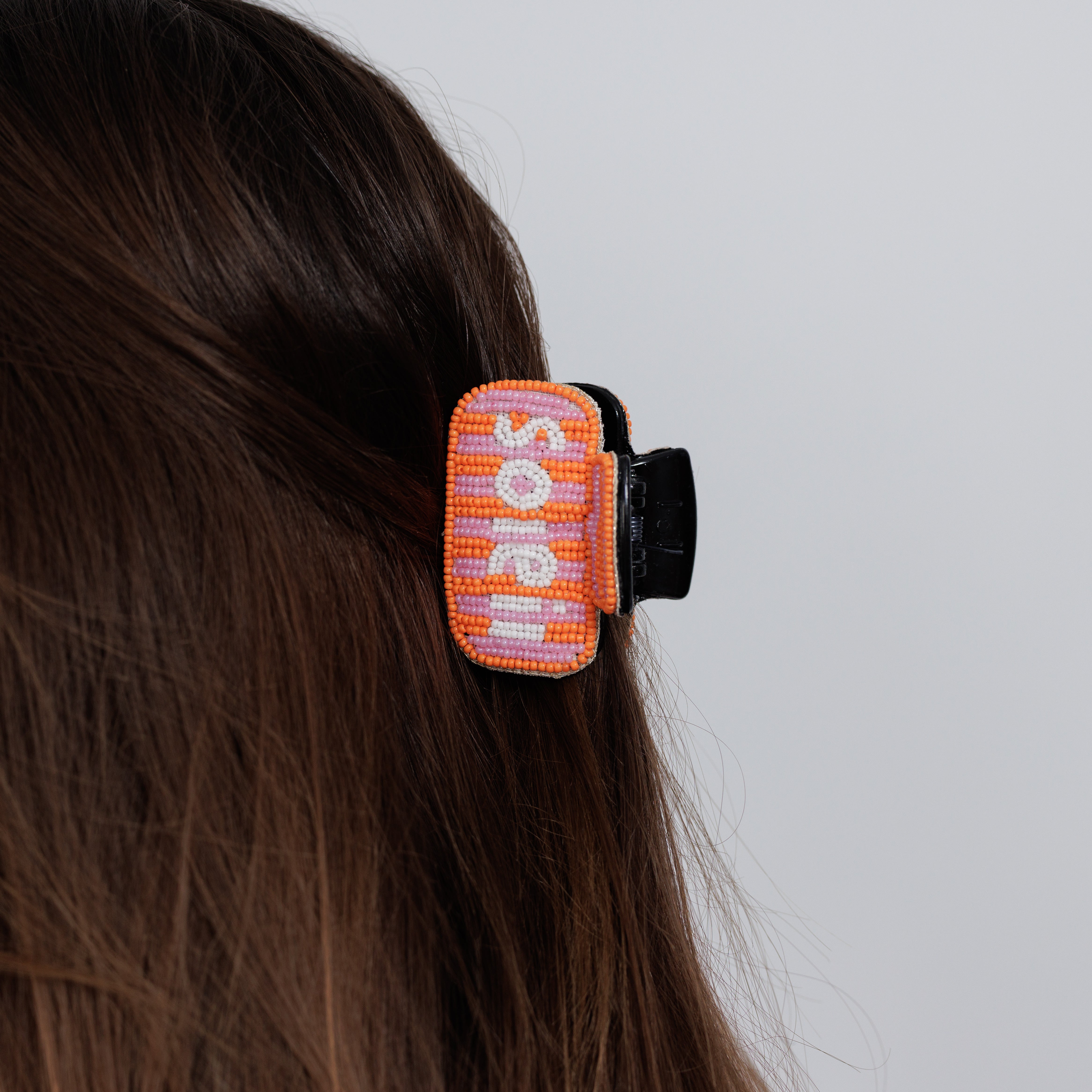 The beaded soleil claw clip worn in loose brown hair, seen from behind.