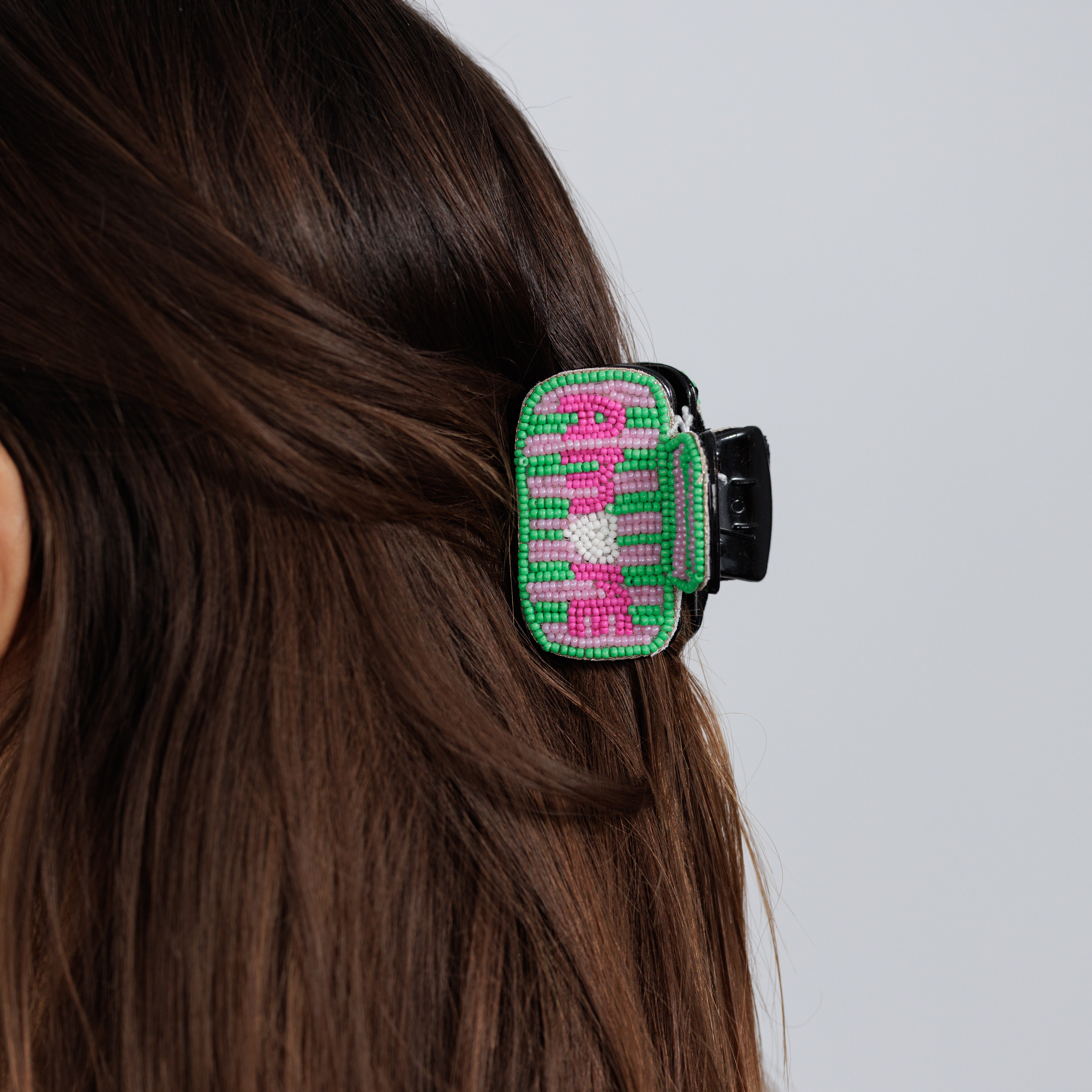 The beaded AMORE claw clip worn in brown hair, side view.