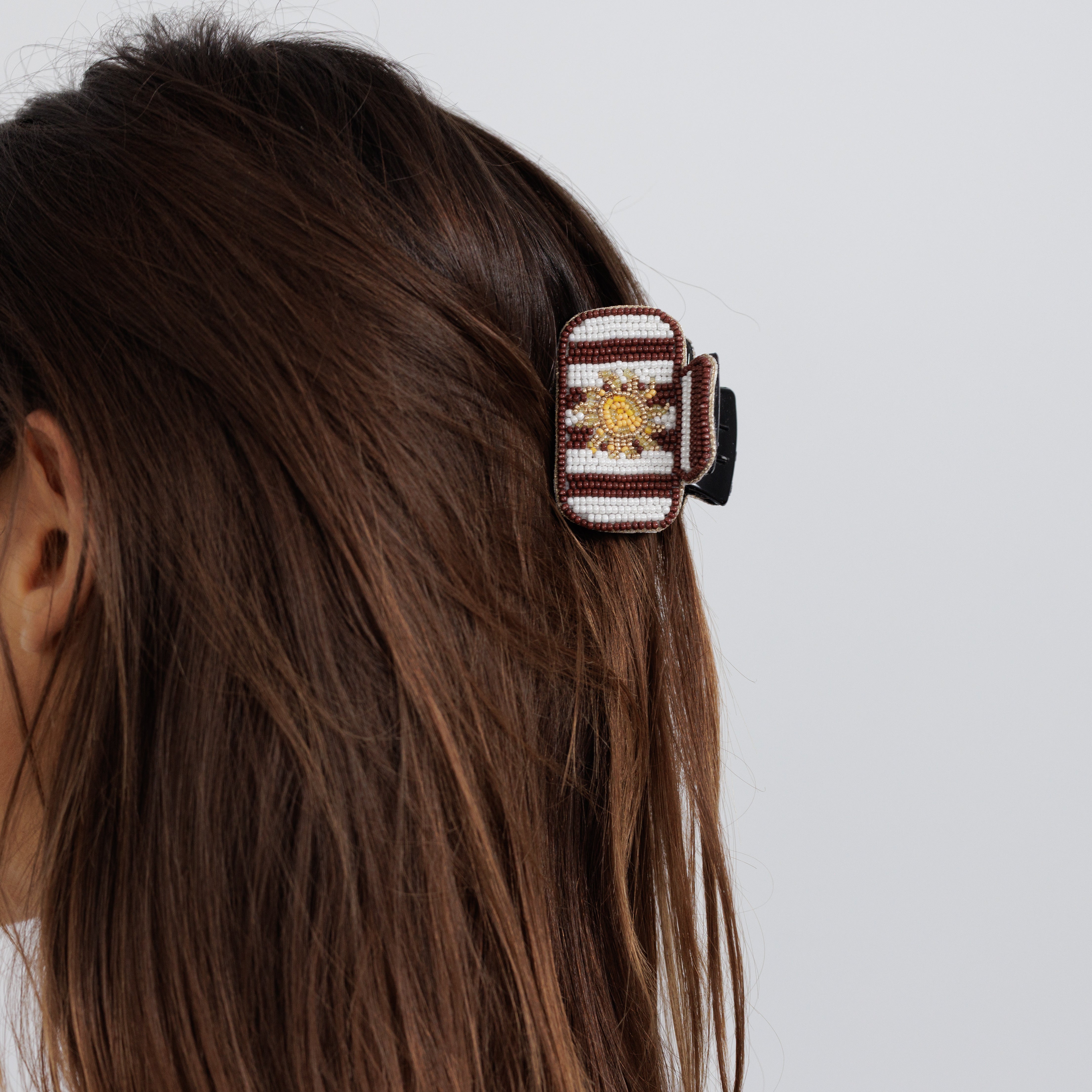 The burgundy striped beaded claw clip worn in loose brown hair.