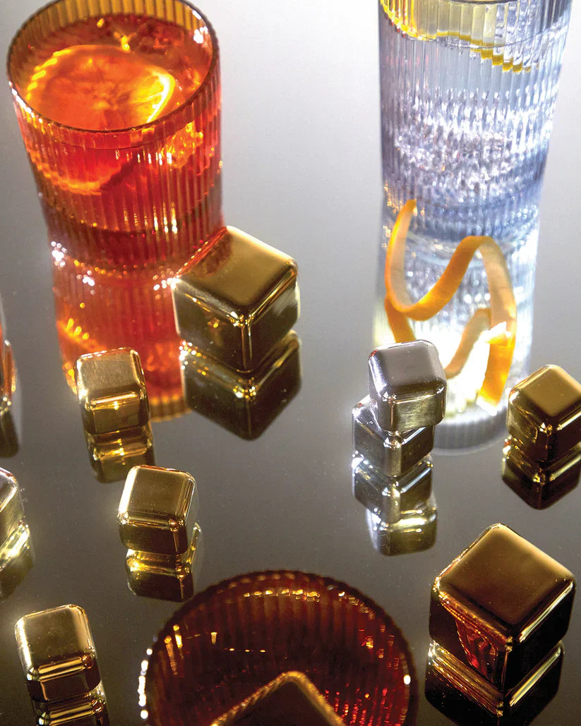 Gold and silver chilling cubes scattered between cocktail glasses, a styled shot