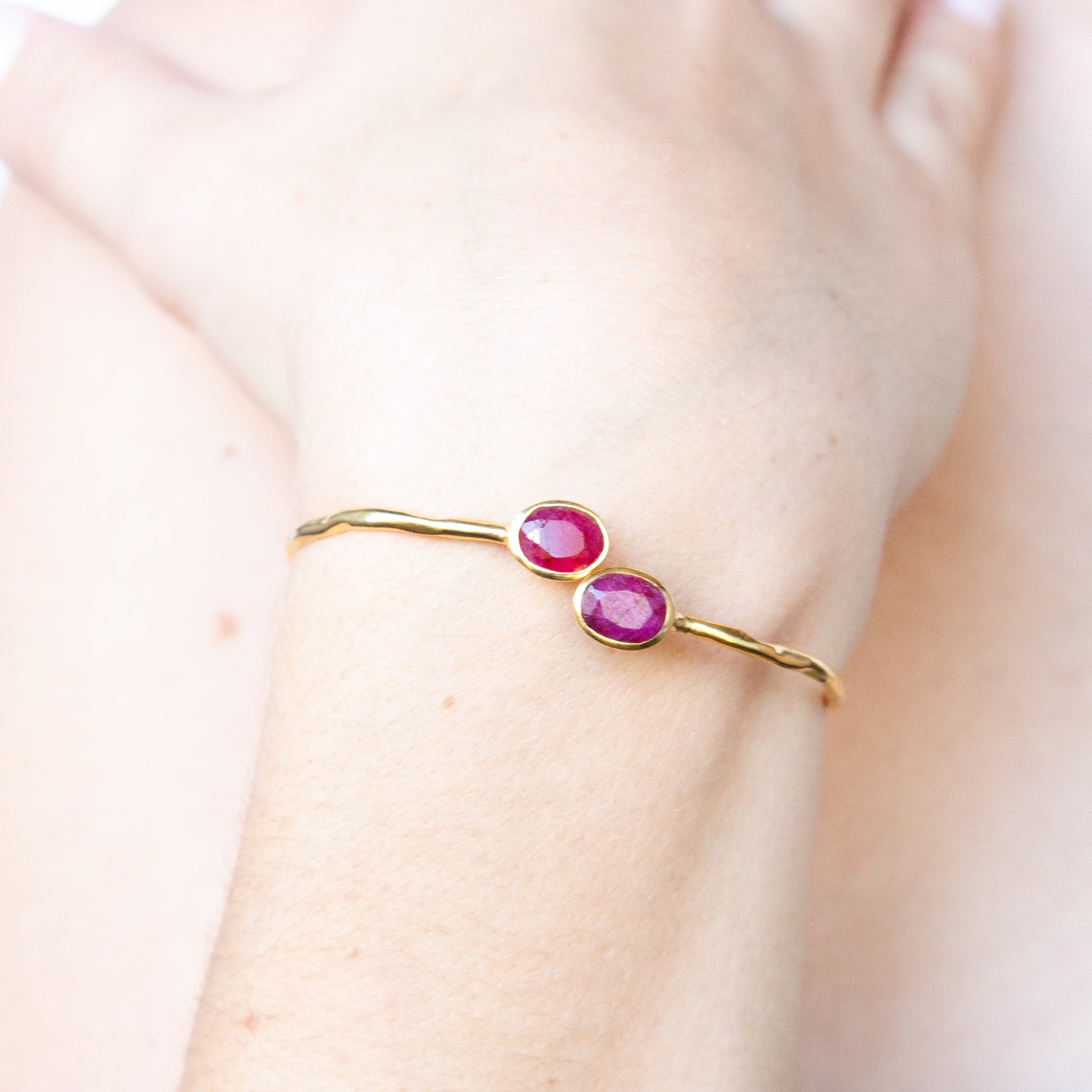 Fine Euro Gold cuff bangle with two ruby-pink oval gems worn on a wrist