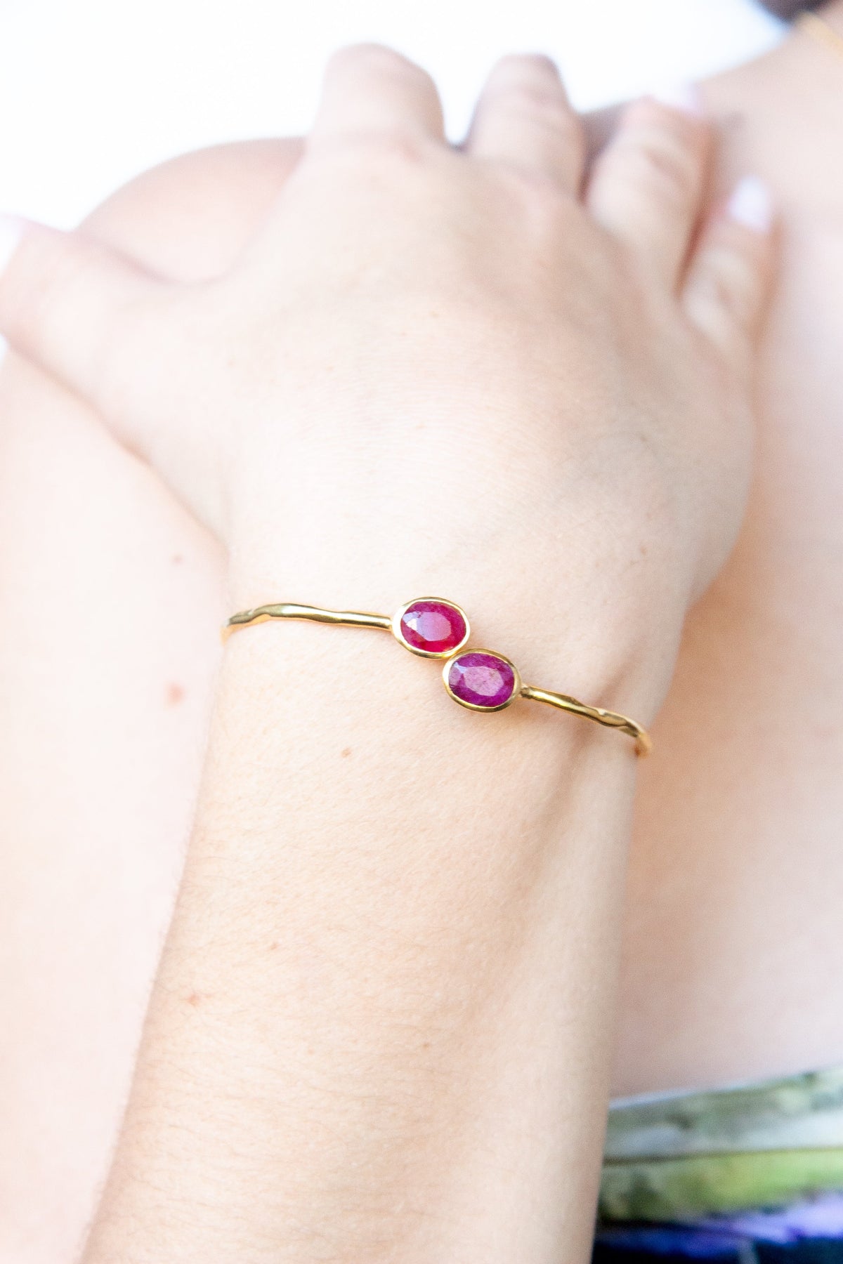 Fine Euro Gold cuff bangle with two ruby-pink oval gems worn on a wrist
