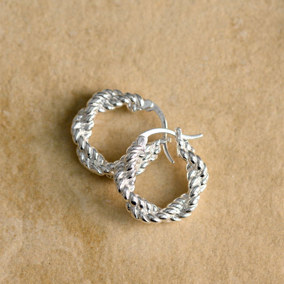 Two Stevie silver hoops resting together, showing the twisted rope texture and hinged catch