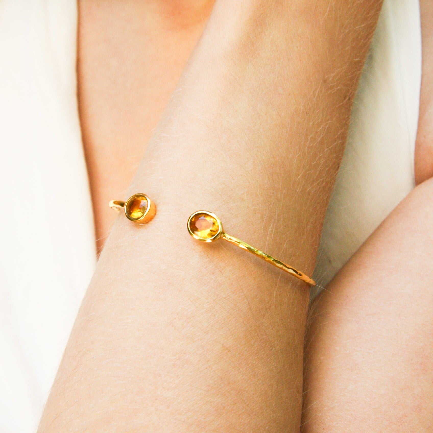 Model wearing a fine Euro Gold cuff bangle with two citrine-yellow gems on the wrist