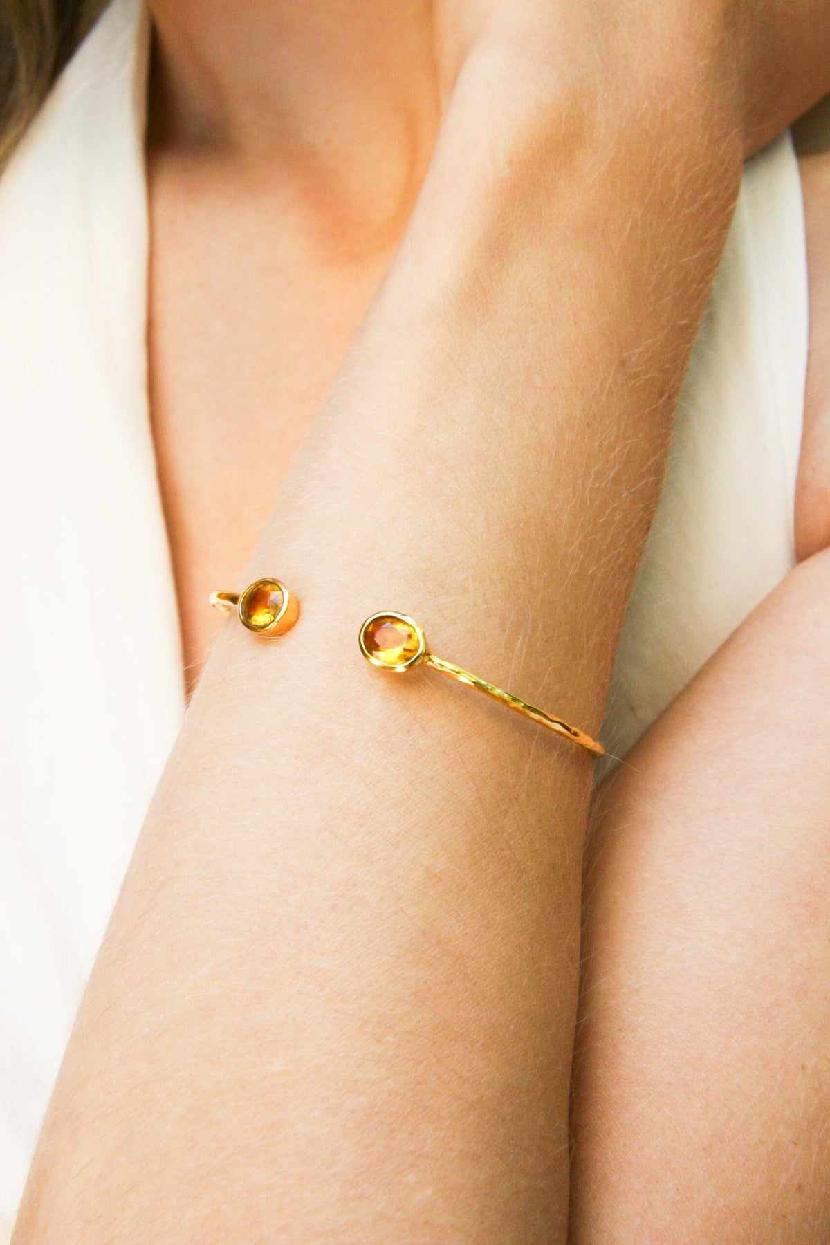 Model wearing a fine Euro Gold cuff bangle with two citrine-yellow gems on the wrist
