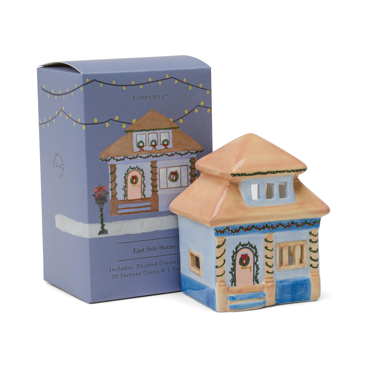 Painted ceramic house with pale blue walls, a peach roof, garlands and a wreath on the pink door, beside its blue illustrated gift box.