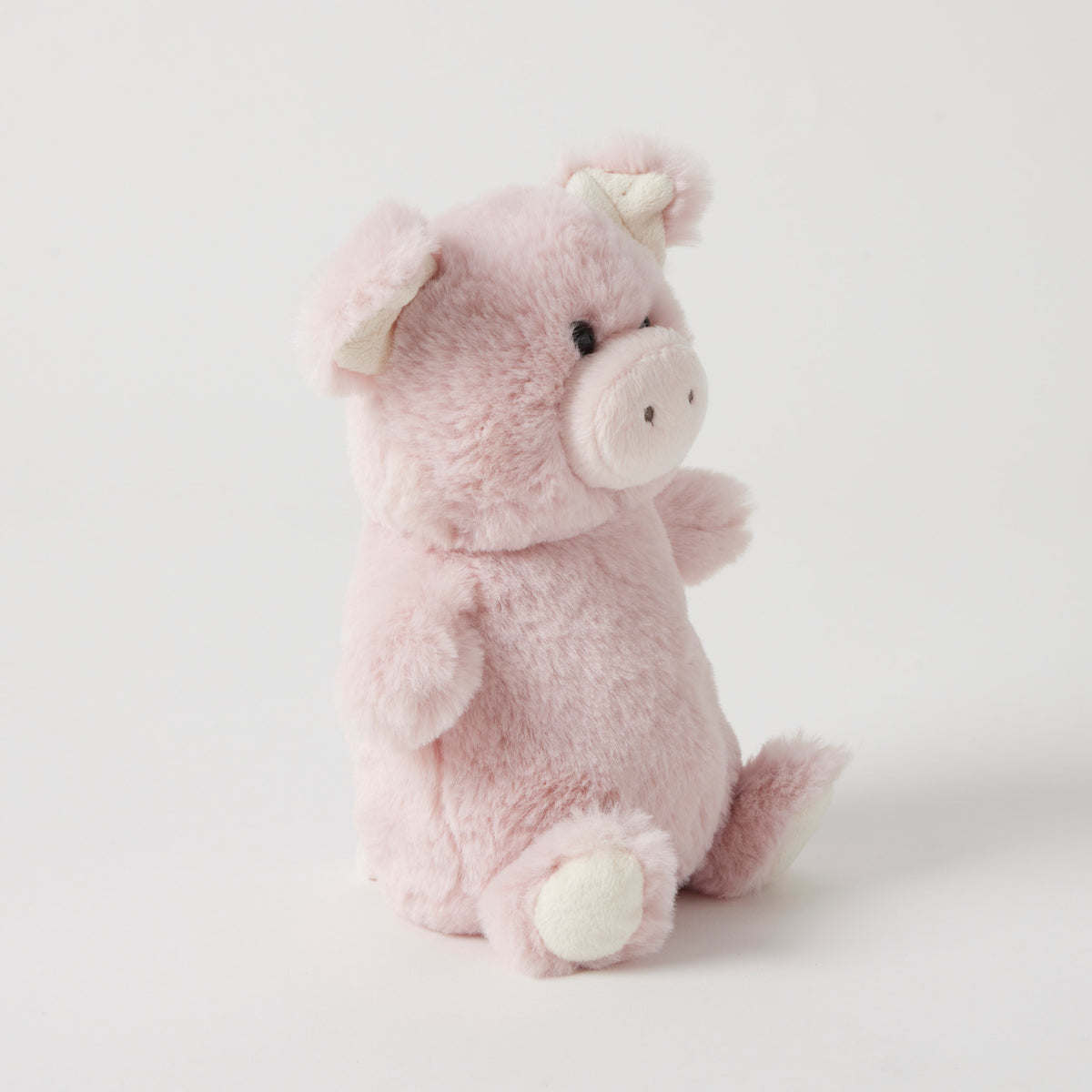 The pink piglet rattle from the side, showing its round body and cream feet