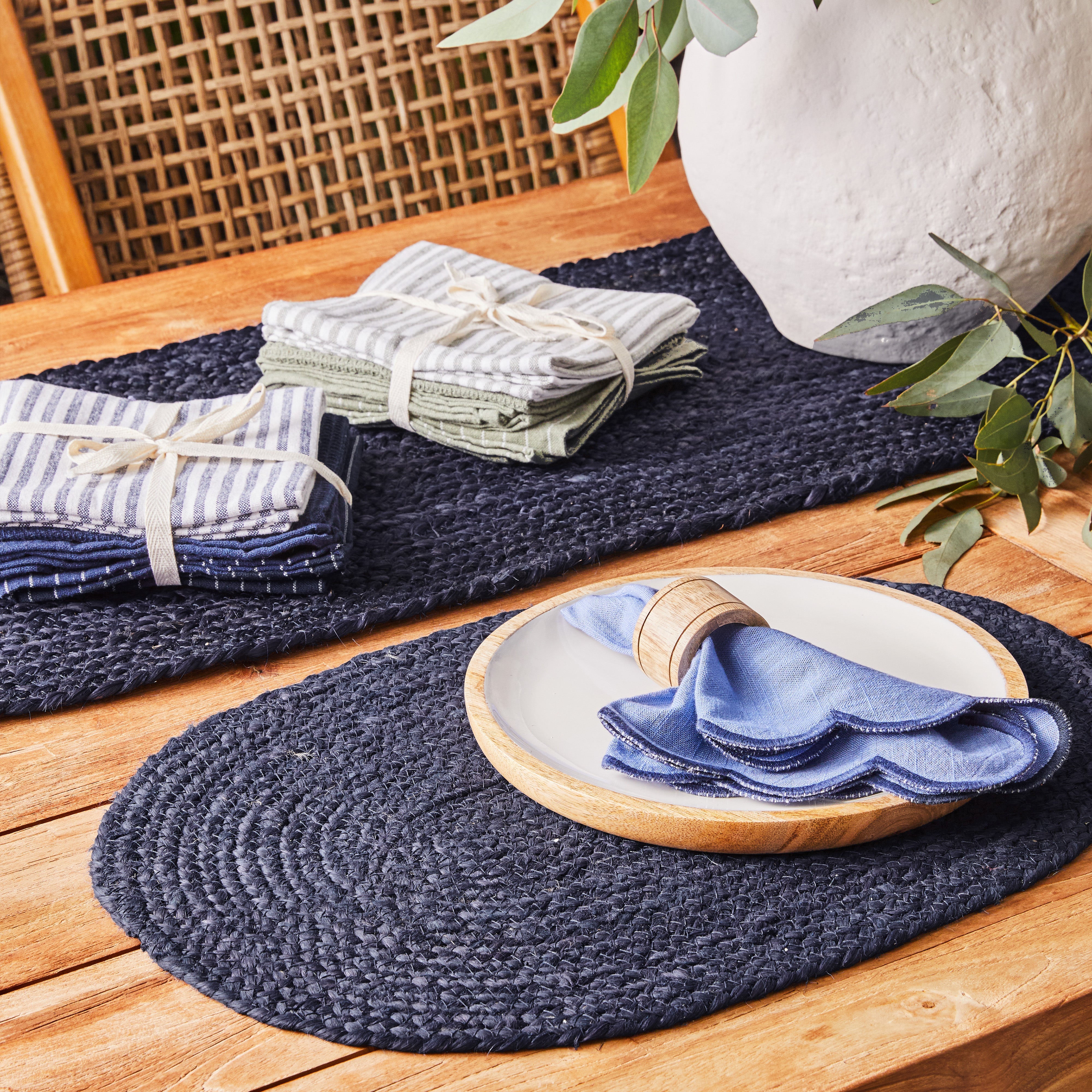 Katerina tea towel bundles styled on navy woven placemats at an outdoor table