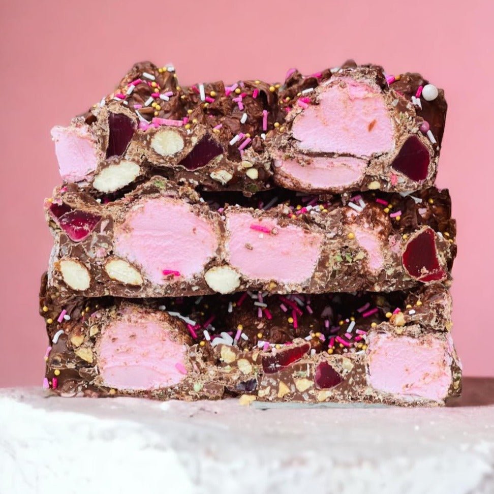 Stacked slices of Lovers Lane rocky road with pink raspberry marshmallow, almonds and sprinkles in chocolate