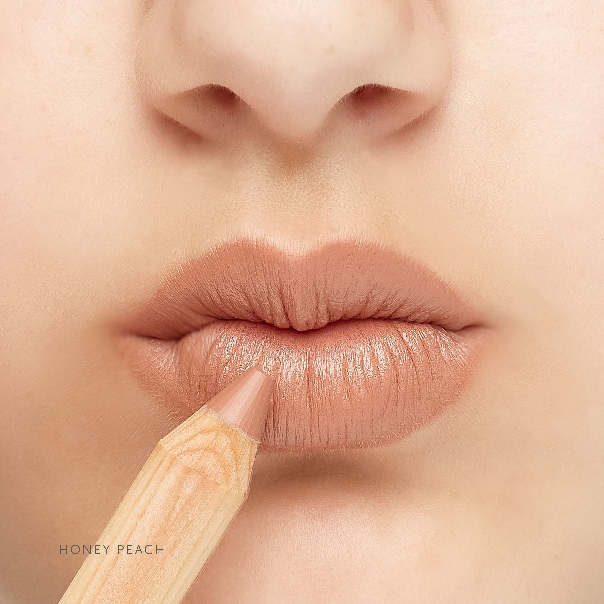 Lük Beautifood natural lipstick crayon in Honey Peach — worn on lips, shown with the pencil