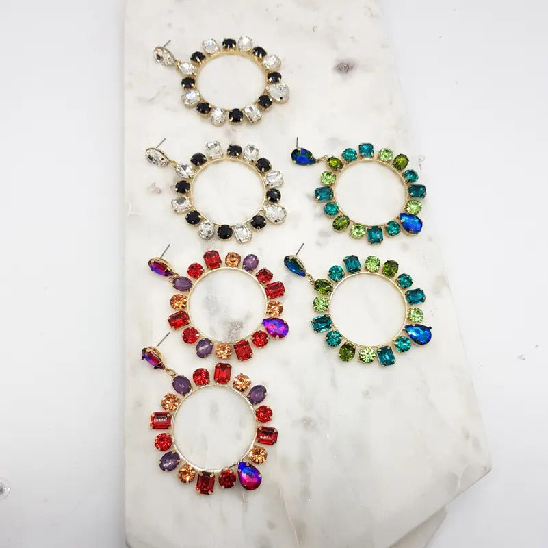 Assorted crystal circle drop earrings in red, green and black mixes on a marble tile