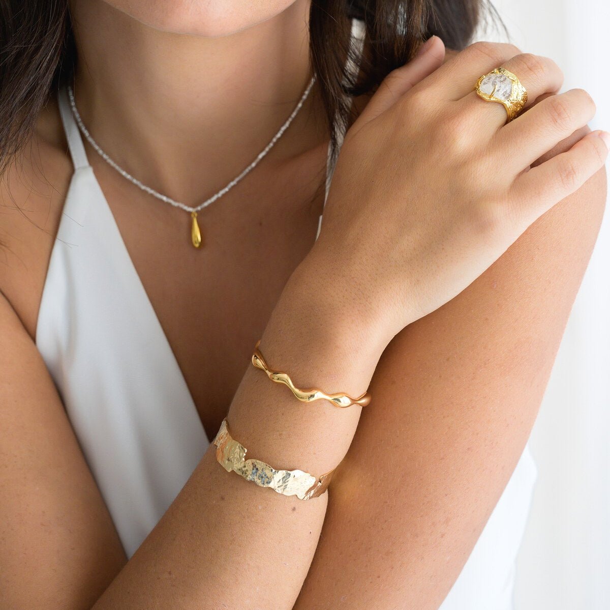 Model wearing the Nohea gold ring with gold bangles and a fine necklace