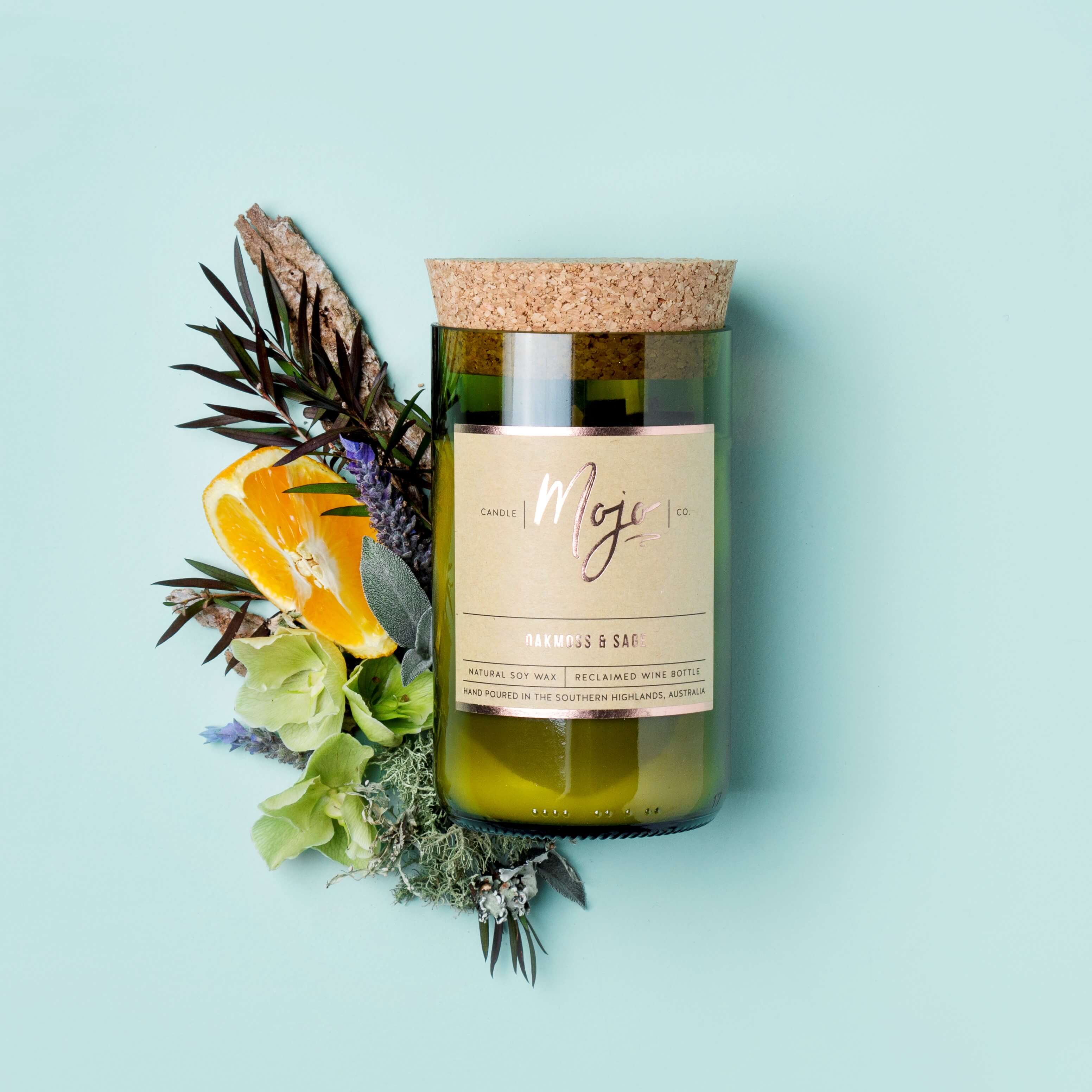 Oakmoss & Sage soy candle in a cork-topped reclaimed wine bottle with rosemary, lavender and orange