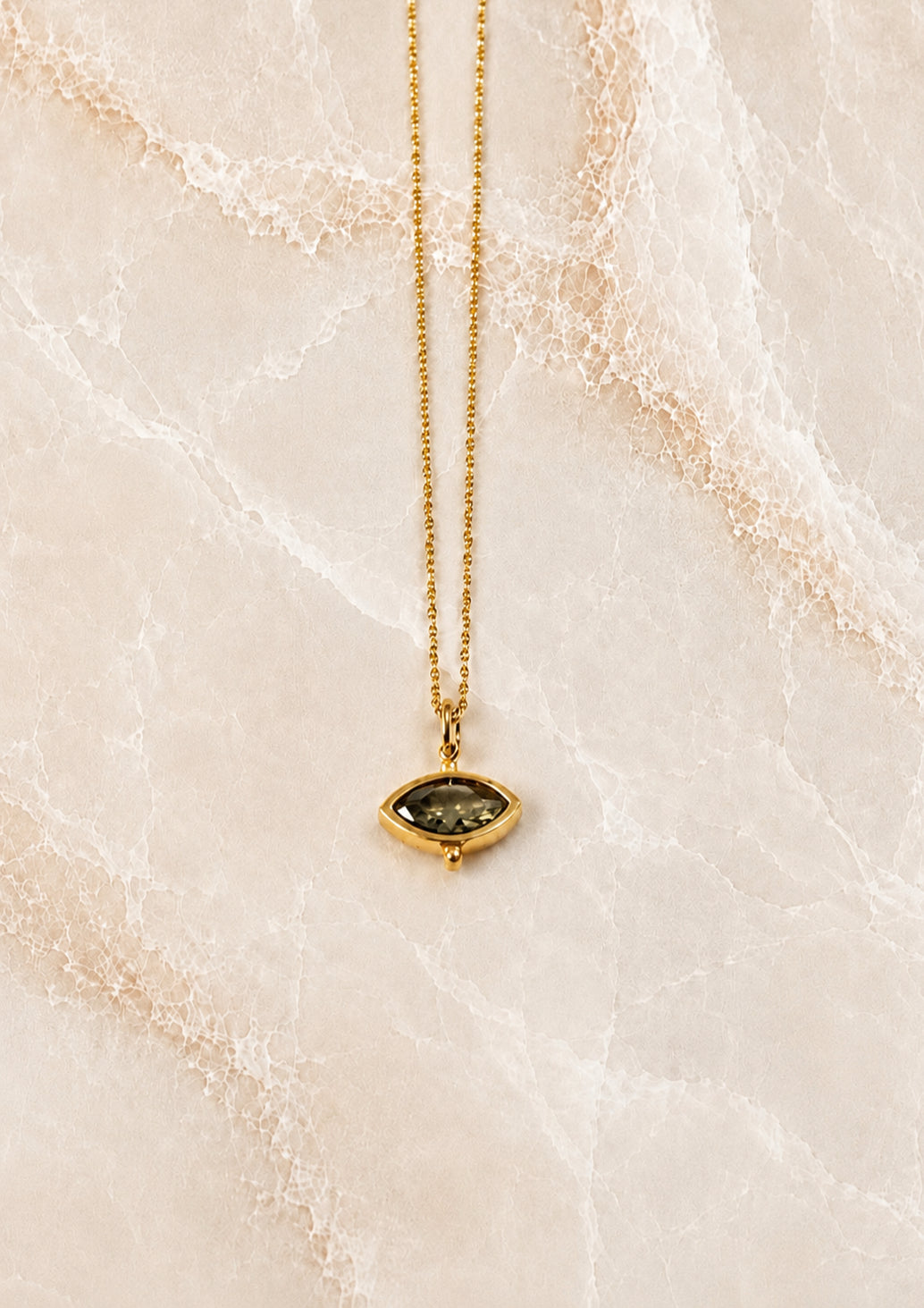 Fine gold chain necklace with a small olive-green marquise stone pendant in a beaded gold setting