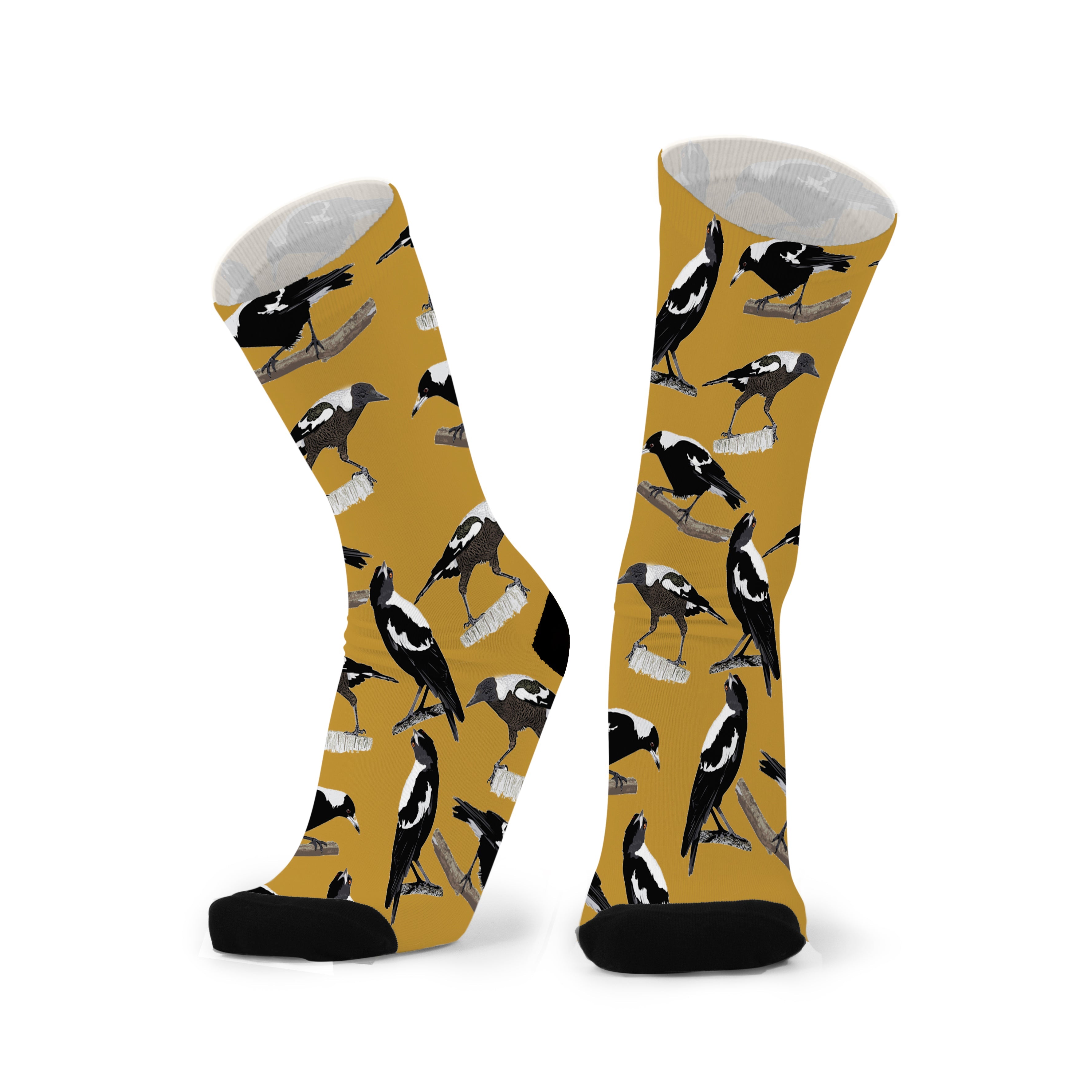 Pair of warm mustard socks with black toes, printed with black and white magpies strutting and swooping.