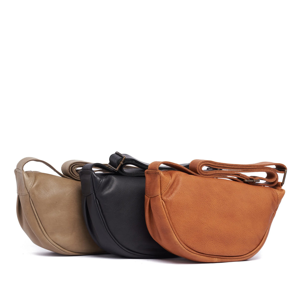 Half-moon cross body bags lined up in latte, black and tan