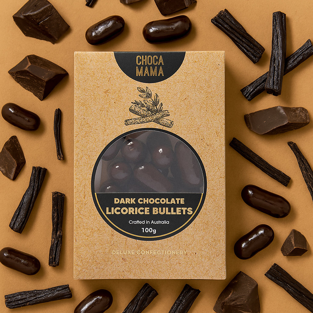 Licorice bullets box on tan among dark chocolate chunks, licorice root sticks and loose bullets