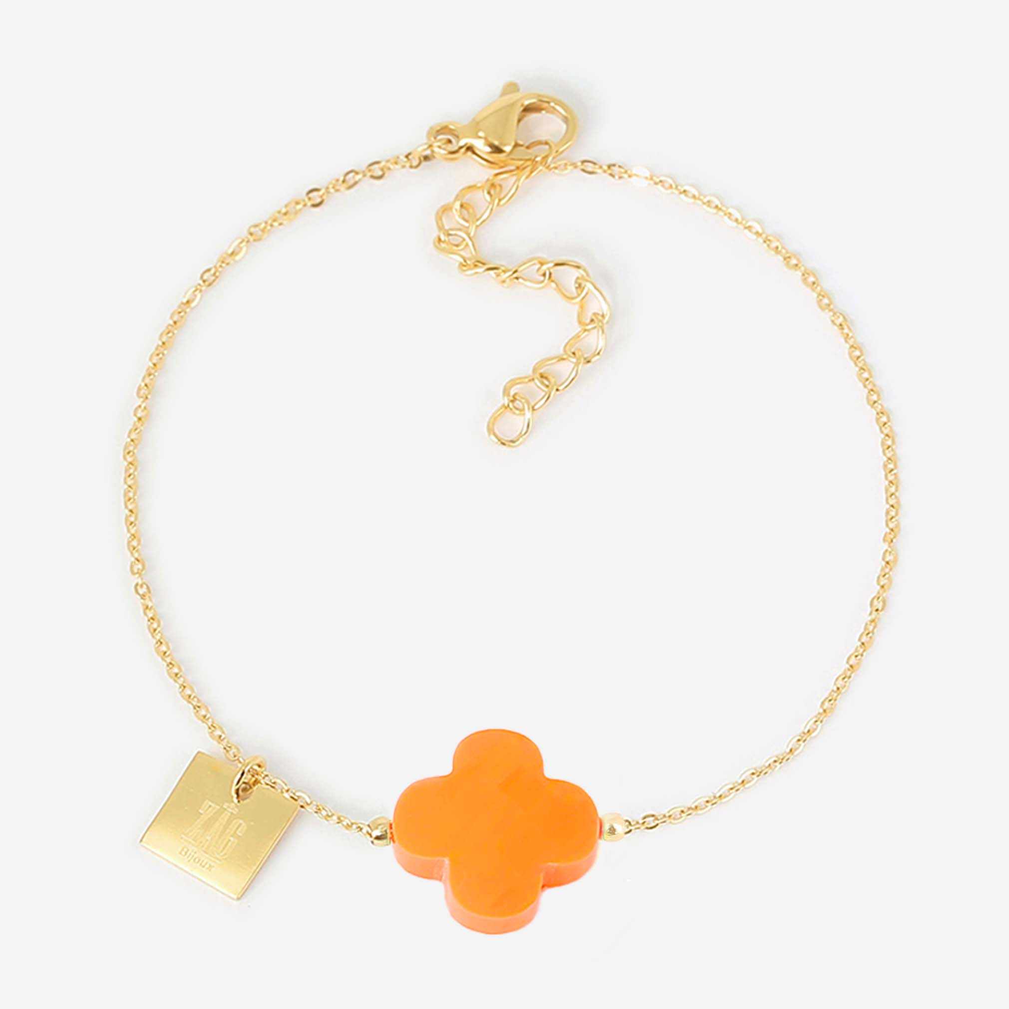 Fine gold chain bracelet with an orange glass four-leaf clover and a small engraved gold tag
