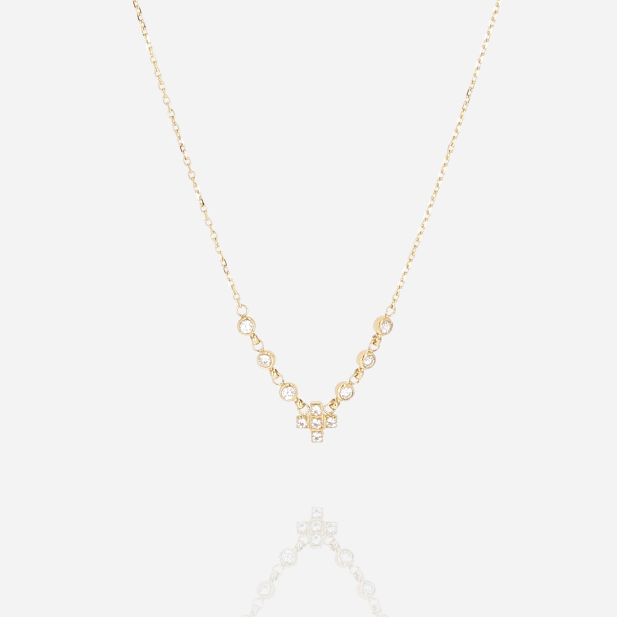Fine gold chain necklace with a small crystal-set cross pendant and stones along the chain