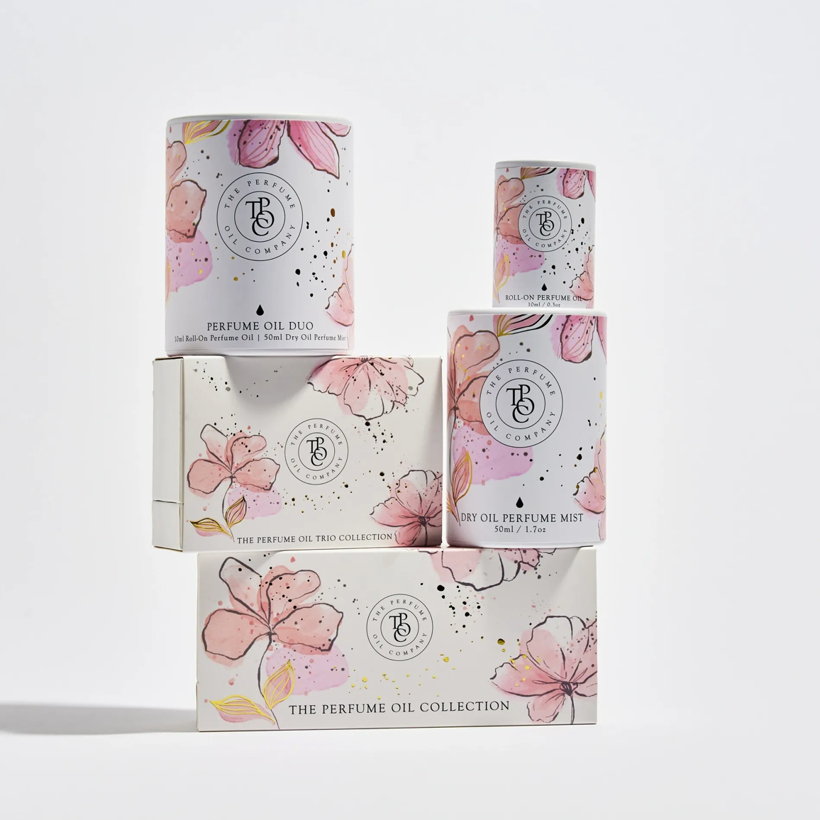 The Perfume Oil Collection floral gift boxes stacked, with pink blossom illustrations