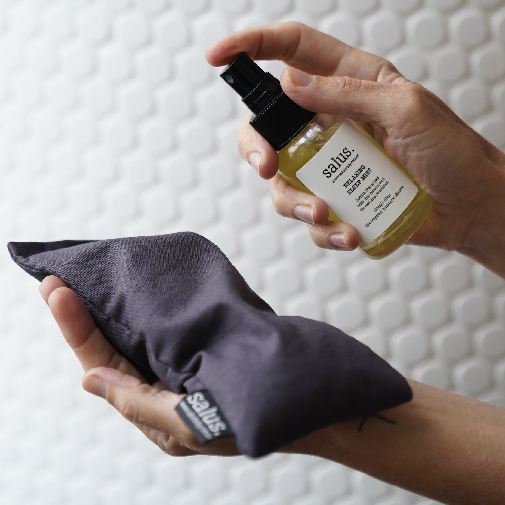 Spraying Salus Relaxing Sleep Mist over a charcoal Salus eye pillow