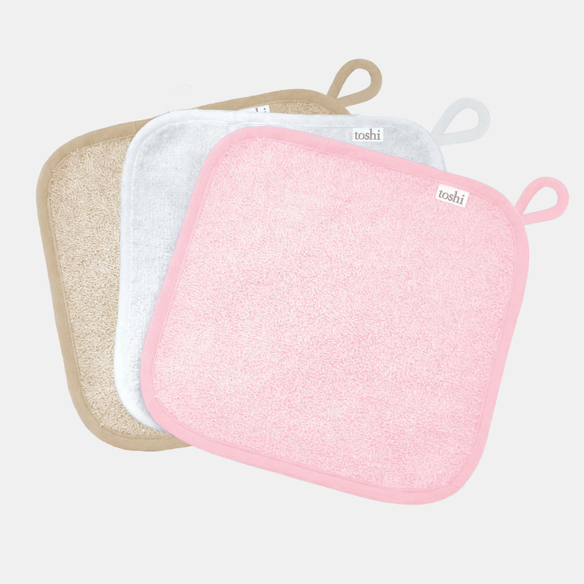 Three Toshi baby washcloths in pink, white and sand cotton towelling, each with a hanging loop