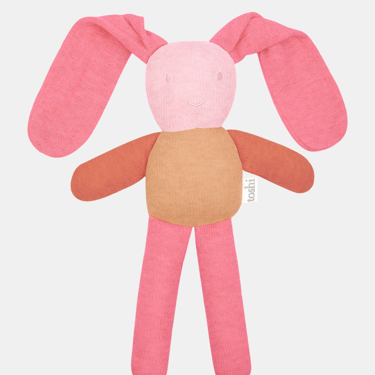 Toshi Bunny Bobby knitted comforter in misty rose — long floppy coral ears, a soft pink face with an embroidered smile, rust arms and pink legs